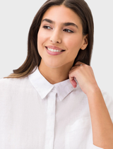 Vicki's white linen shirt featured on a hanger, emphasizing its breathable material and simple style.