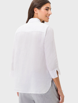 A white linen shirt by Vicki, elegantly hanging, highlighting its soft texture and relaxed fit.