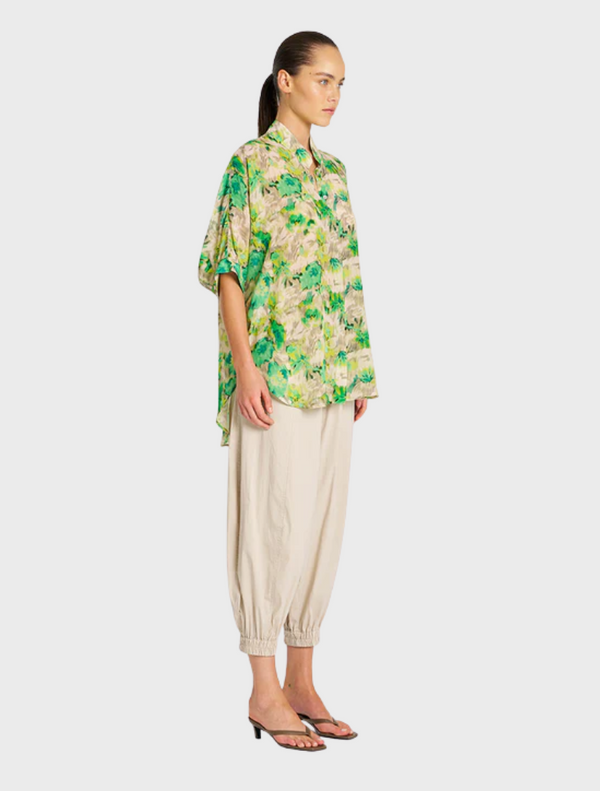 The model is dressed in a green and yellow floral shirt, highlighting a lively and colorful design.