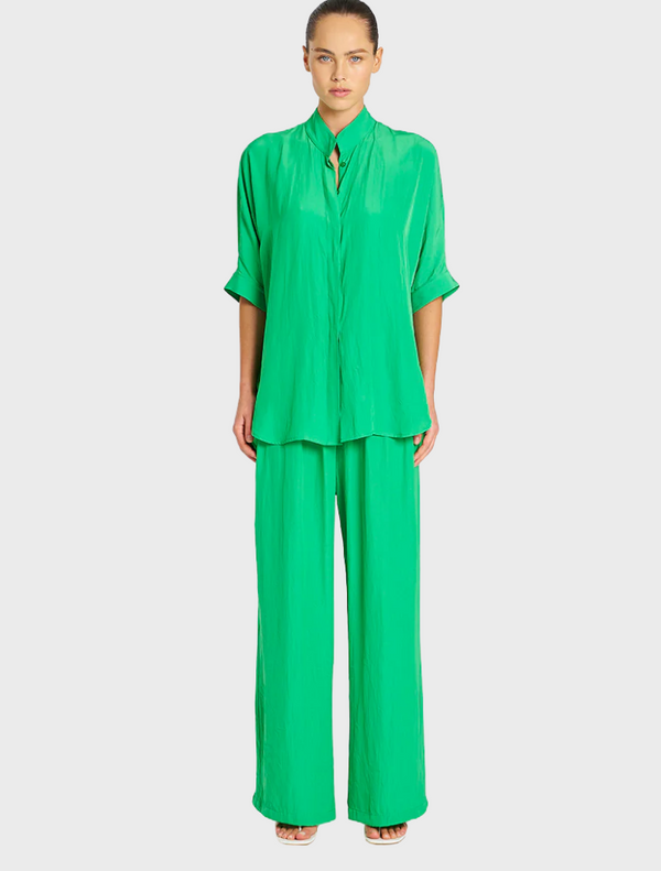Green silk pajama set displayed on a neutral background, showcasing its smooth texture and elegant design.
