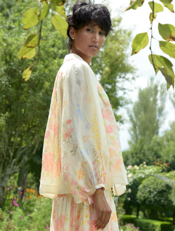 A woman wearing a floral dress walks leisurely in a park, enjoying the natural scenery around her.