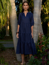Indigo ramie tiered midi dress with V-neck, full sleeves, elastic cuffs, raw bias trim, and discreet side seam pockets.