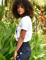 A woman wearing a white t-shirt featuring a bow design, posing confidently with a soft smile.c