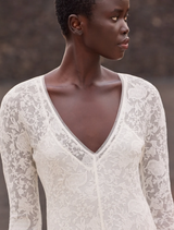 Refined long off-white dress with delicate lace, V-neck, and flounce hem, perfect for romantic summer celebrations.