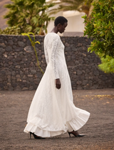 Timeless off-white dress with delicate lace, V-neck, and airy flounce hem, suitable for special summer ceremonies.