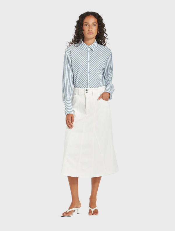 The model showcases a blue and white striped shirt and a white skirt, presenting a fresh and fashionable look.