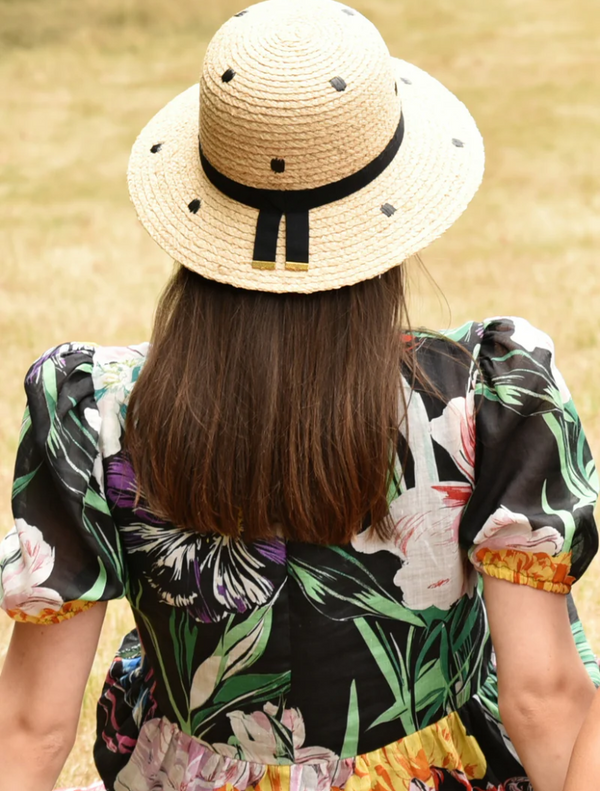 A woman in a floral dress and a straw hat, embodying a cheerful summer vibe.
