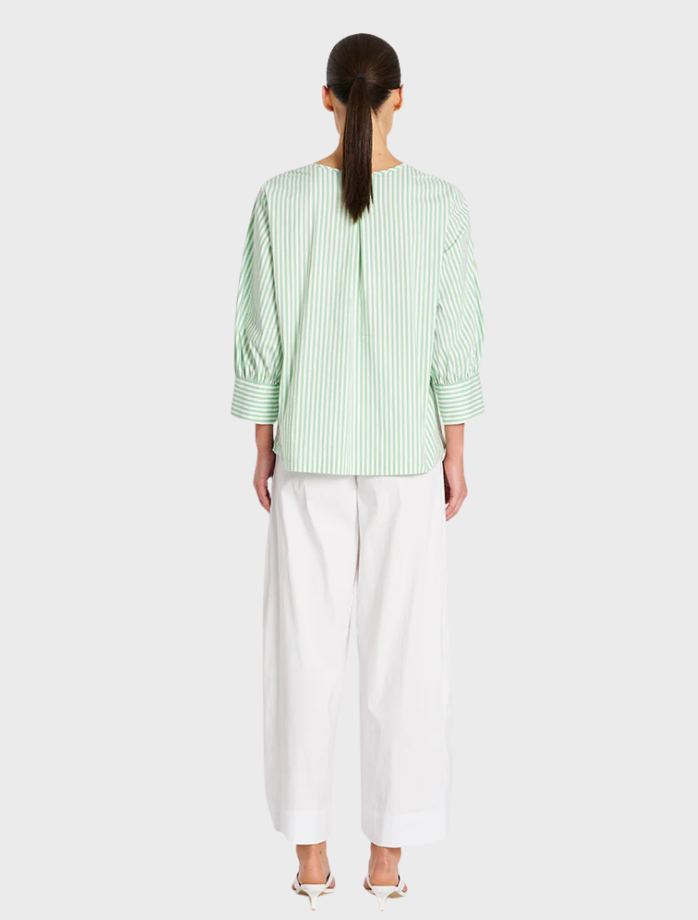The image features a model in a green top and white wide-legged pants, reflecting a stylish and relaxed outfit choice.