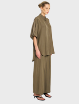 Model features an olive green shirt and wide Fossil Pace Pants, exemplifying a chic and laid-back fashion choice.