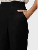 Black Willow Trousers designed with a wide-leg silhouette, made from breathable materials, featuring embroidery on the front leg and an elasticized back for added comfort.