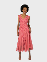 A Willow V-neck cocktail dress in a soft blossom color, featuring a flared godet design for an elegant silhouette.