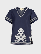 A blue Border Control Top presented on a hanger, illustrating its stylish appearance and material.