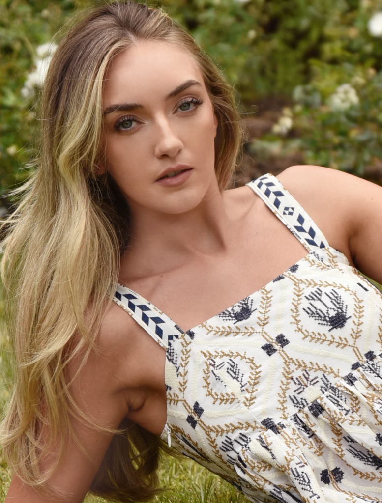 A model displays a blue and white floral print dress, accentuating its lovely design and fashionable appeal.