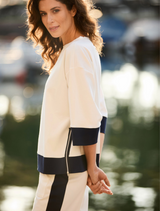 A model is seen in a white top and navy pants, exemplifying a stylish and polished ensemble.