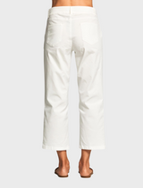 A woman in a blue top and white pants stands, exemplifying a chic and casual look suitable for various occasions.