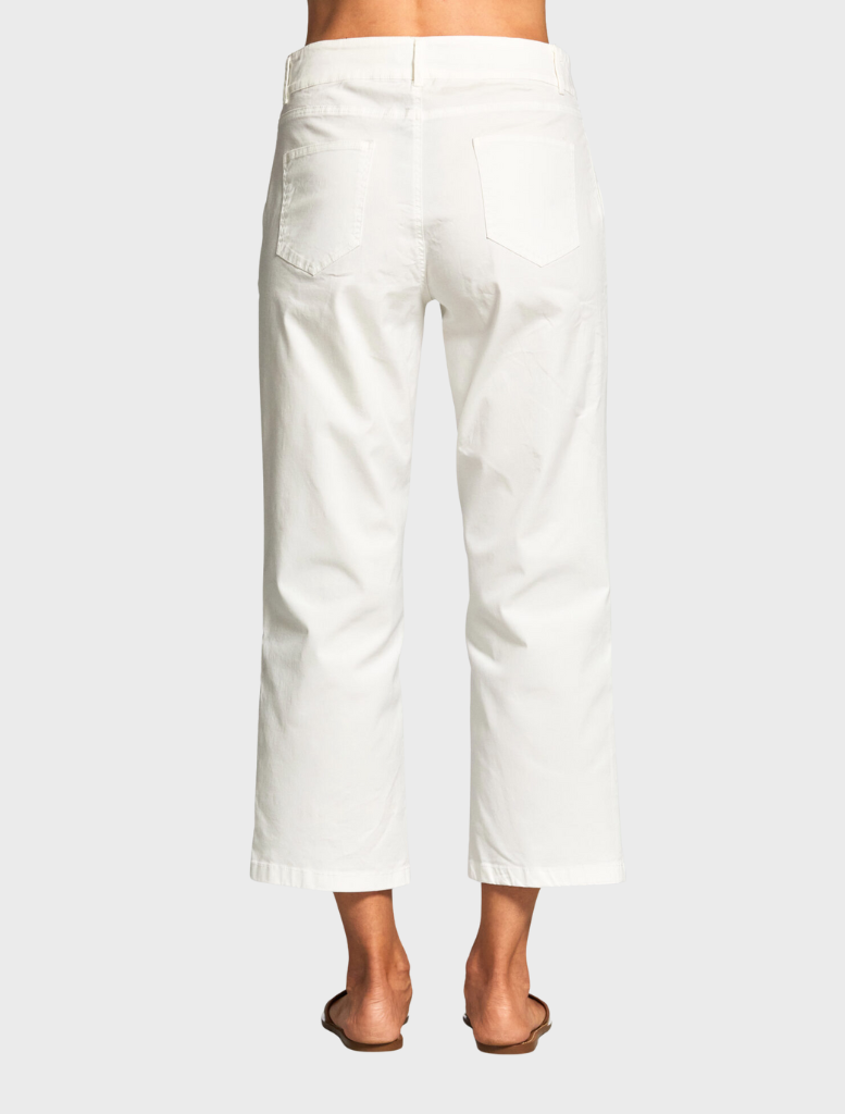 A woman in a blue top and white pants stands, exemplifying a chic and casual look suitable for various occasions.