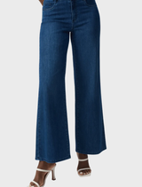 A woman models medium blue Goldie wide leg denim jeans, showcasing a stylish and relaxed fit.