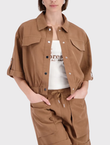 Model wearing a mocca jacket with ¾ sleeves, featuring a shirt collar and snap button placket, showcasing modern style.