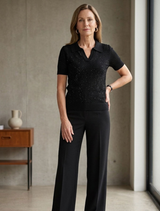 Black knit top displayed on a hanger, showcasing its texture and design.