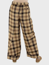  A woman models brown and black checkered trousers, showcasing a stylish and comfortable outfit.