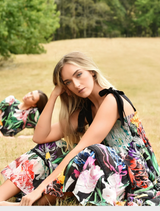 A woman is seen in a floral print dress, displaying a beautiful pattern of flowers in vivid hues.