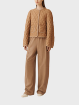 Light brown coats hanging on racks, featuring diverse styles and materials in a fashion retail environment.