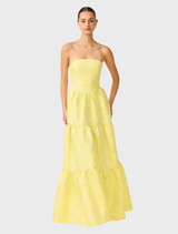 A vibrant yellow strapless gown hanging, featuring a fitted bodice and a full skirt, ideal for formal occasions.