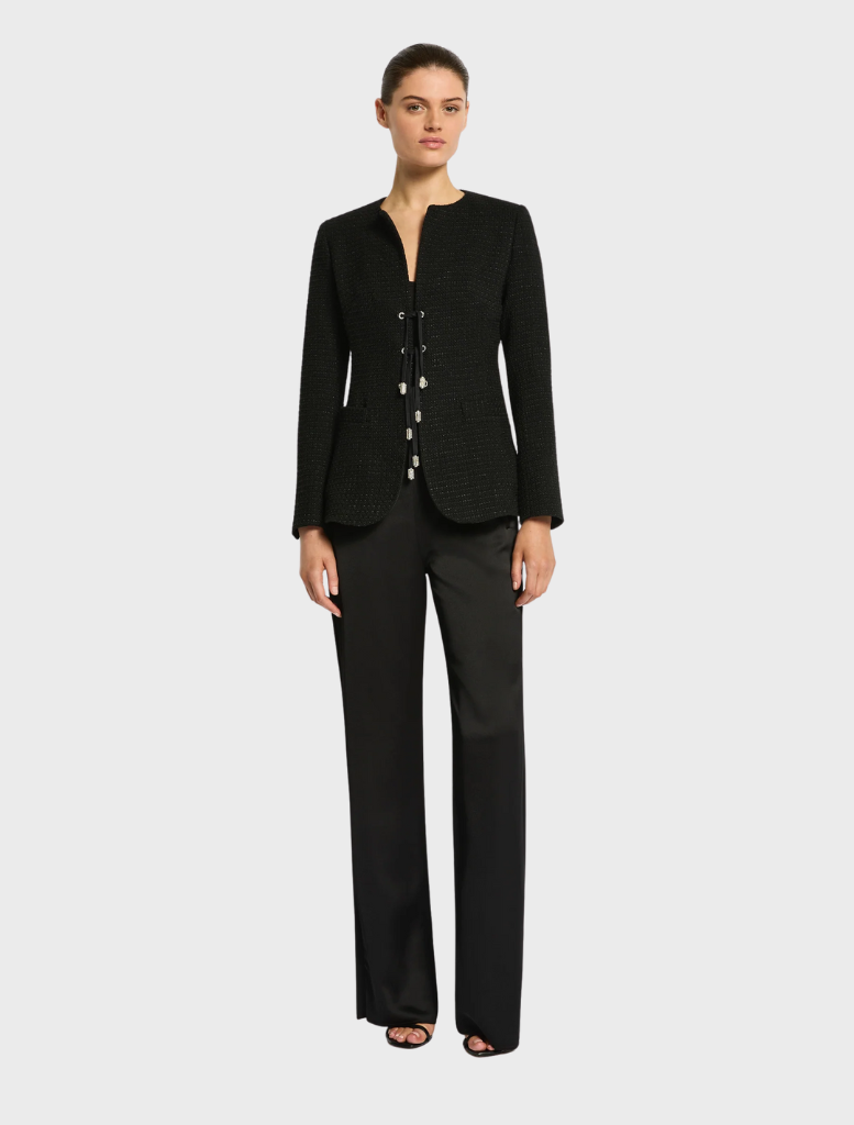 A woman sporting a black suit and shorts, blending formal attire with casual elements.
