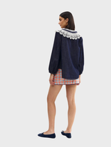Chic indigo denim blouse with lace trim, offering a fashionable blend of casual and refined styles.