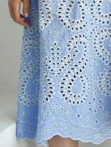 A woman showcases a blue dress with beautiful white lace, exuding elegance and charm.
