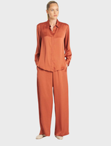 A pair of copper Maxi Pace Pants hanging, highlighting their modern style and vibrant color.