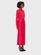  A woman wearing a red dress and black shoes stands confidently, showcasing her stylish outfit.