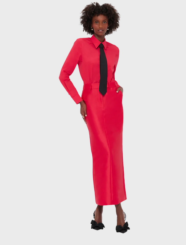 A woman wearing a red dress and a black tie, posing confidently with a stylish expression.