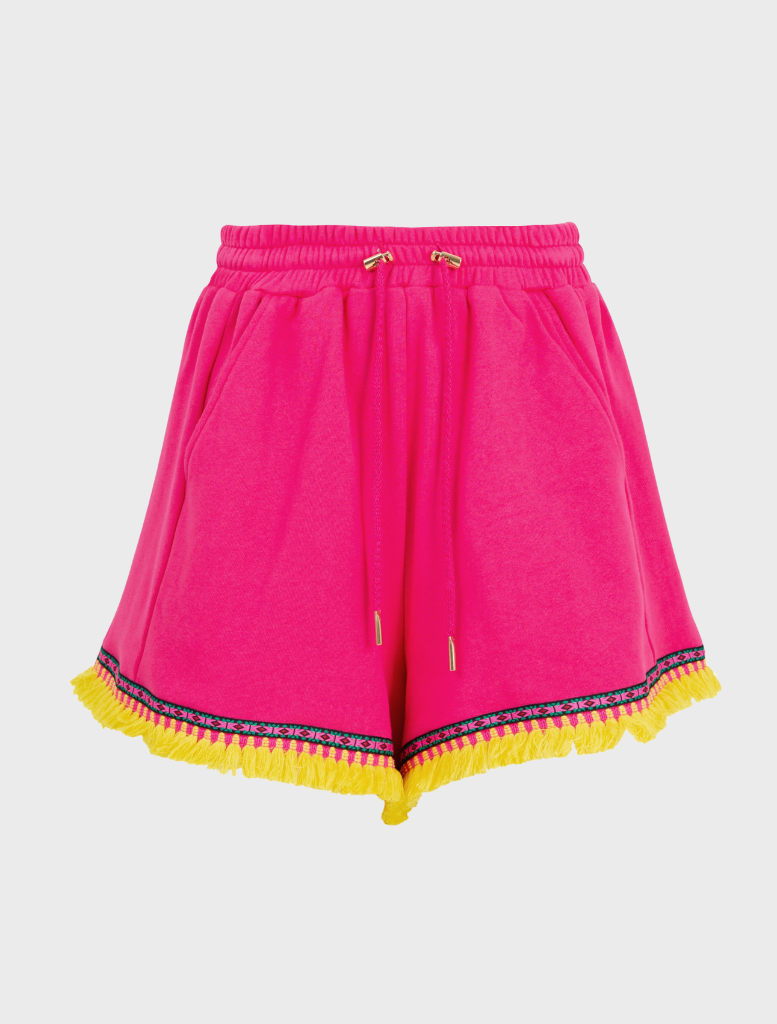  A pink shorts and sneakers poses on a balcony, highlighting her stylish summer outfit.