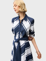 A woman dressed in a blue and white striped maxi dress, posing in a relaxed setting.