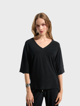 Black top displayed on a hanger, featuring a simple design and short sleeves.
