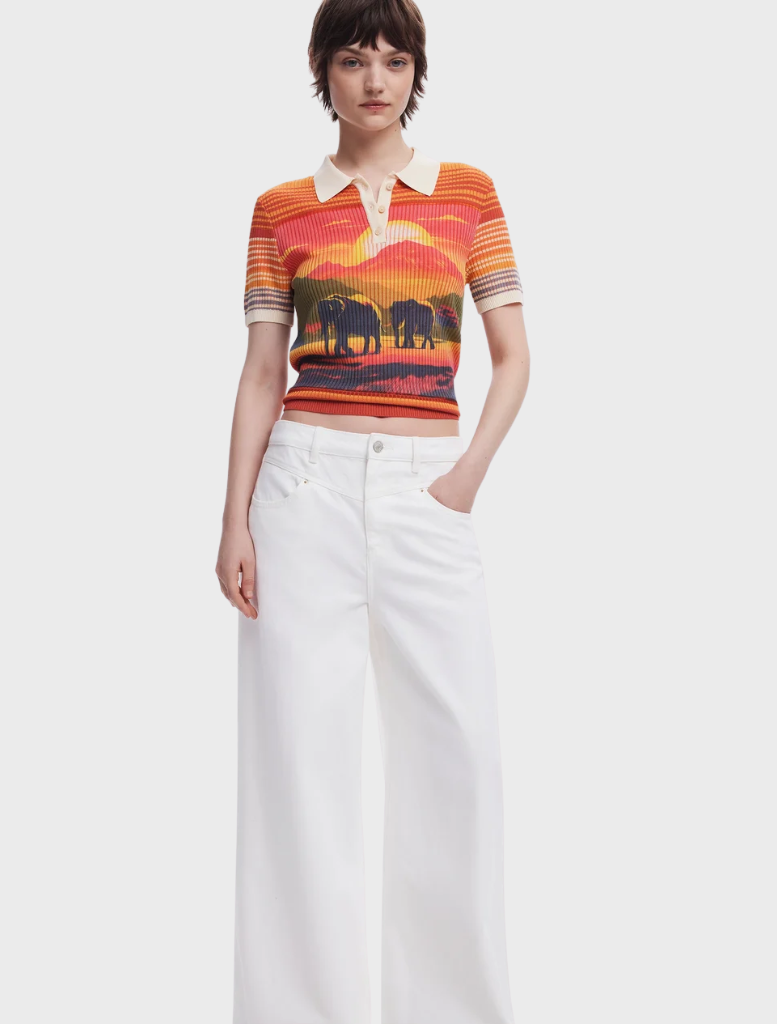 A woman in a polo shirt decorated with an elephant print, exuding a relaxed vibe in a sunny outdoor location.