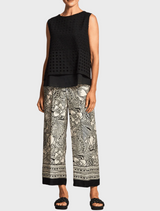 A woman showcases floral print pants, adorned with a bright and eye-catching pattern.
