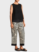 A woman wears floral print pants, highlighting a lively and fashionable design.