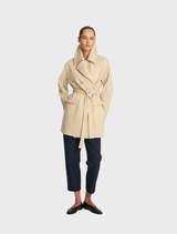 Wrap trench coat in bisque color, featuring a belted waist and long sleeves, perfect for layering in cooler weather.