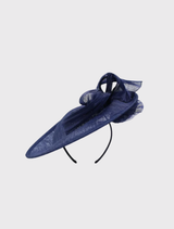  Elegant navy blue fascinator featuring a sculptural ribbon design on a circular base, mounted on a simple headband.