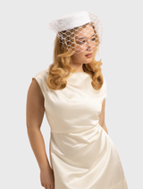 White Zahra Pillbox Hat by Morgan & Taylor, featuring a classic shape and bold veiling for a sophisticated look at events.

