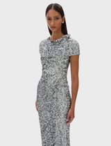 Silver Zayn gown with a sleek design, highlighted by its flowing fabric and refined style, presented on a display.