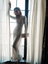 Full-length silver Ziva Gown designed for formal occasions, featuring a fitted bodice, long sleeves, and hand embellishments.