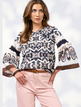  A woman models a floral print blouse, showcasing vibrant colors and a stylish design.