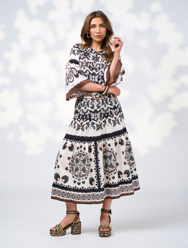 A woman in a floral print blouse stands confidently, highlighting the intricate patterns and colors.