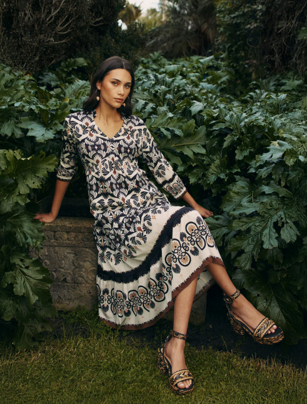  A woman in a beautifully patterned dress, showcasing an elaborate design, posed elegantly for the photograph.
