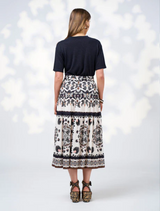 A model is dressed in a sleek black top and a white skirt, highlighting a fashionable look.