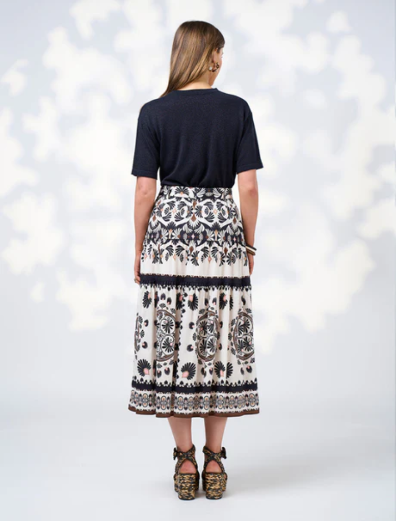 A model is dressed in a sleek black top and a white skirt, highlighting a fashionable look.